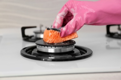 Person cleaning gas stove with sponge, closeup