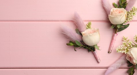 Photo of Many small stylish boutonnieres on pink wooden table, flat lay. Space for text