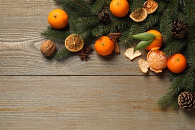 Flat lay Christmas composition with fresh tangerines and fir tree branches on wooden table, space for text