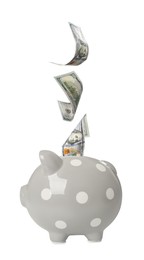 Dollar banknotes falling into grey piggy bank on white background