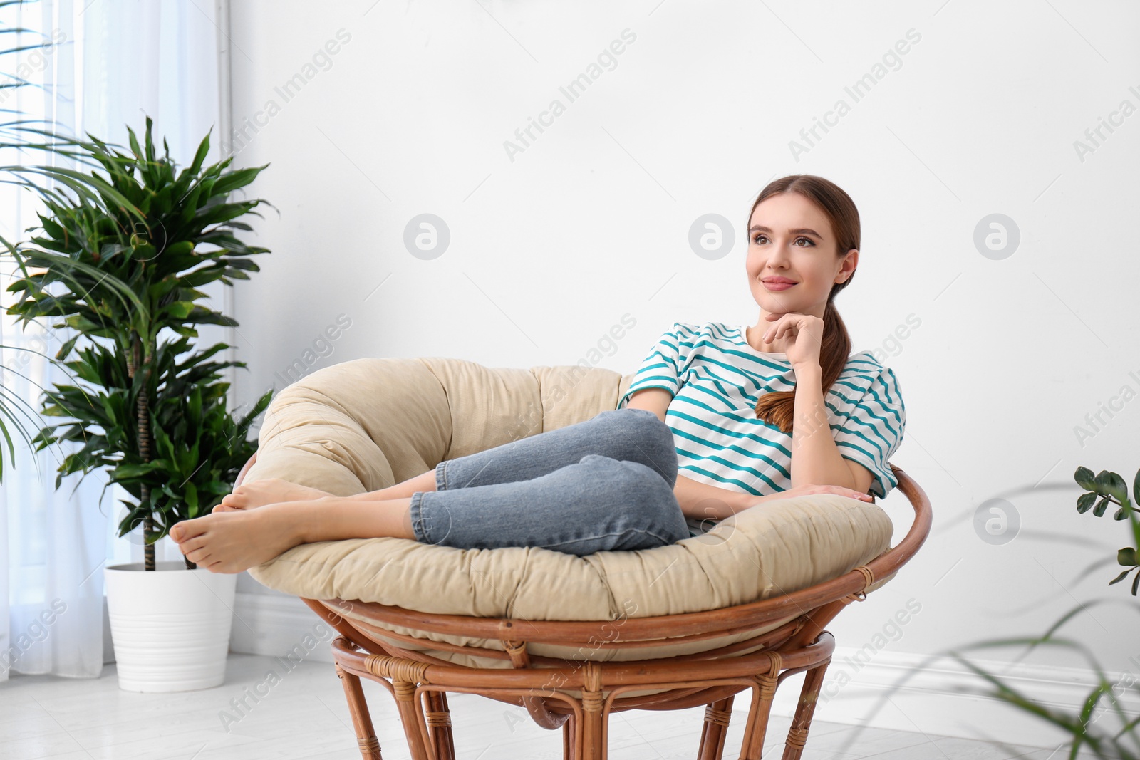 Photo of Young woman in room decorated with plants. Home design