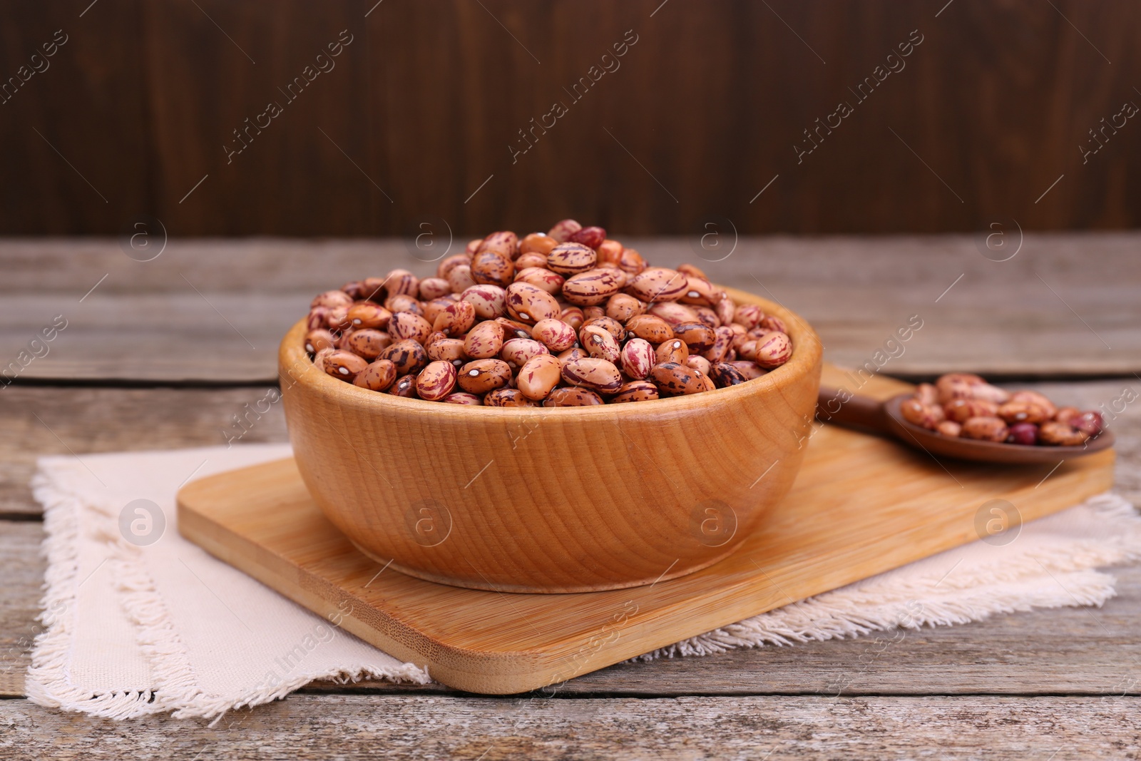 Photo of Bowl with dry kidney beans on old wooden table,