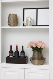 Shelves with different decor and rose flowers indoors. Interior design
