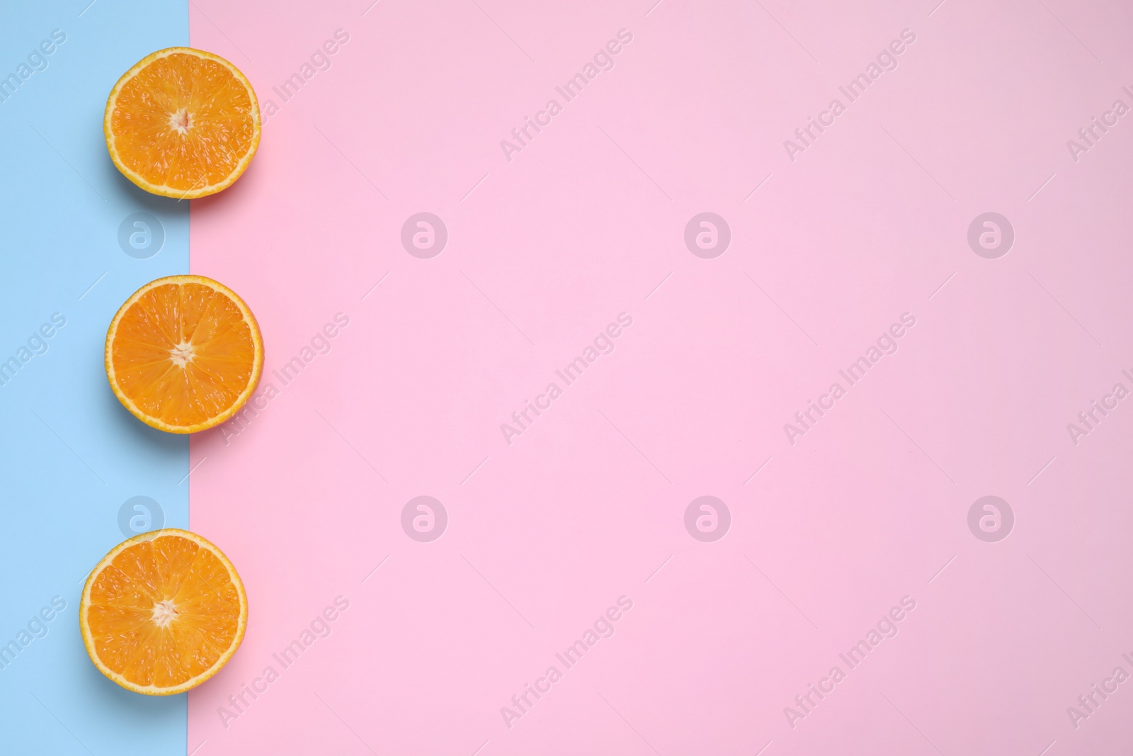 Photo of Cut oranges on color background, flat lay. Space for text