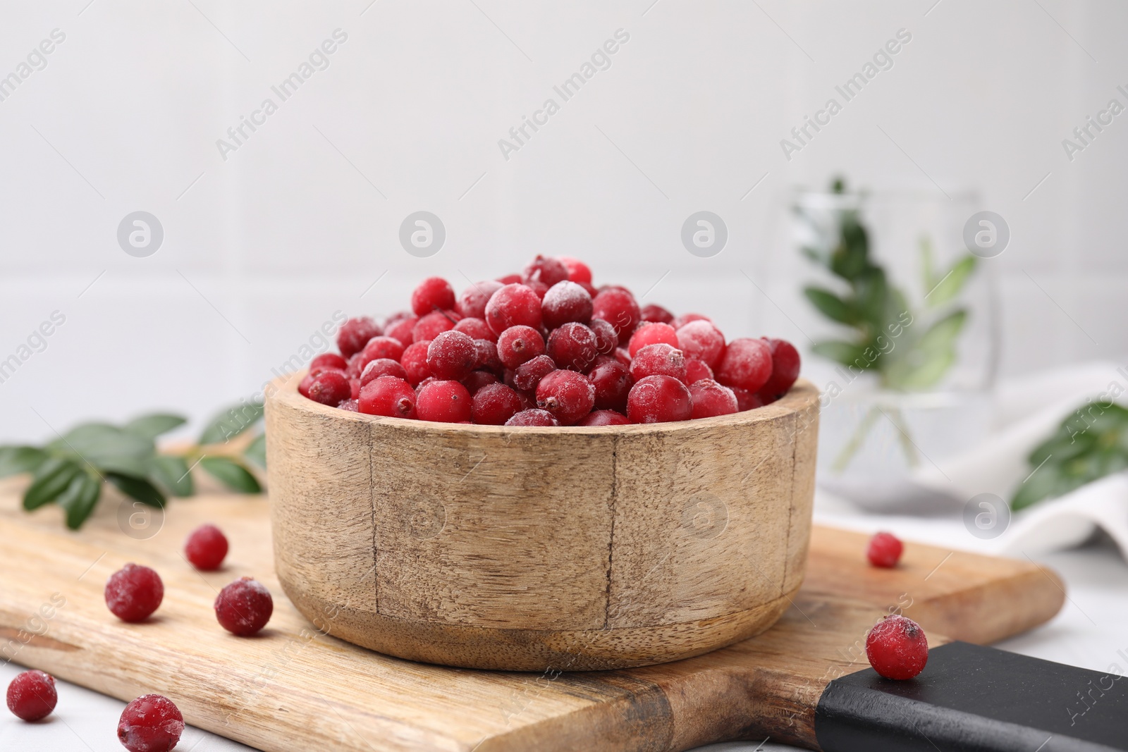 Photo of Frozen red cranberries in bowl on table, closeup