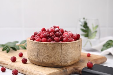 Photo of Frozen red cranberries in bowl on table, closeup