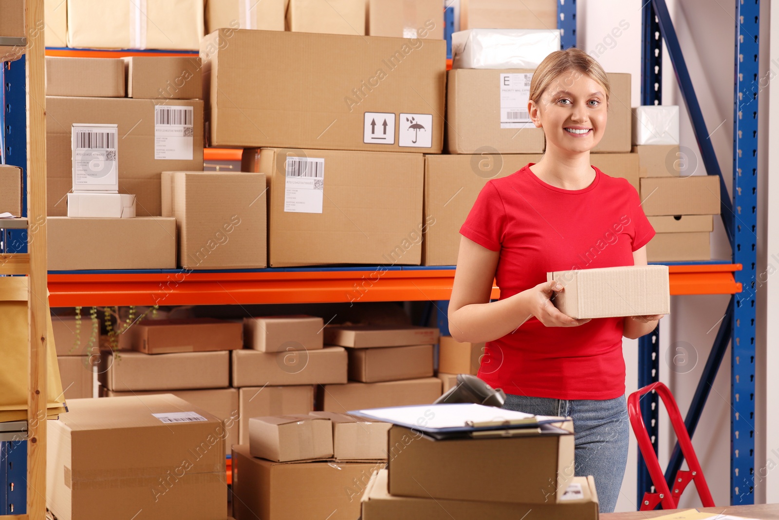 Photo of Post office worker with parcel near rack indoors