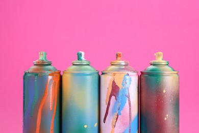 Photo of Many spray paint cans on pink background