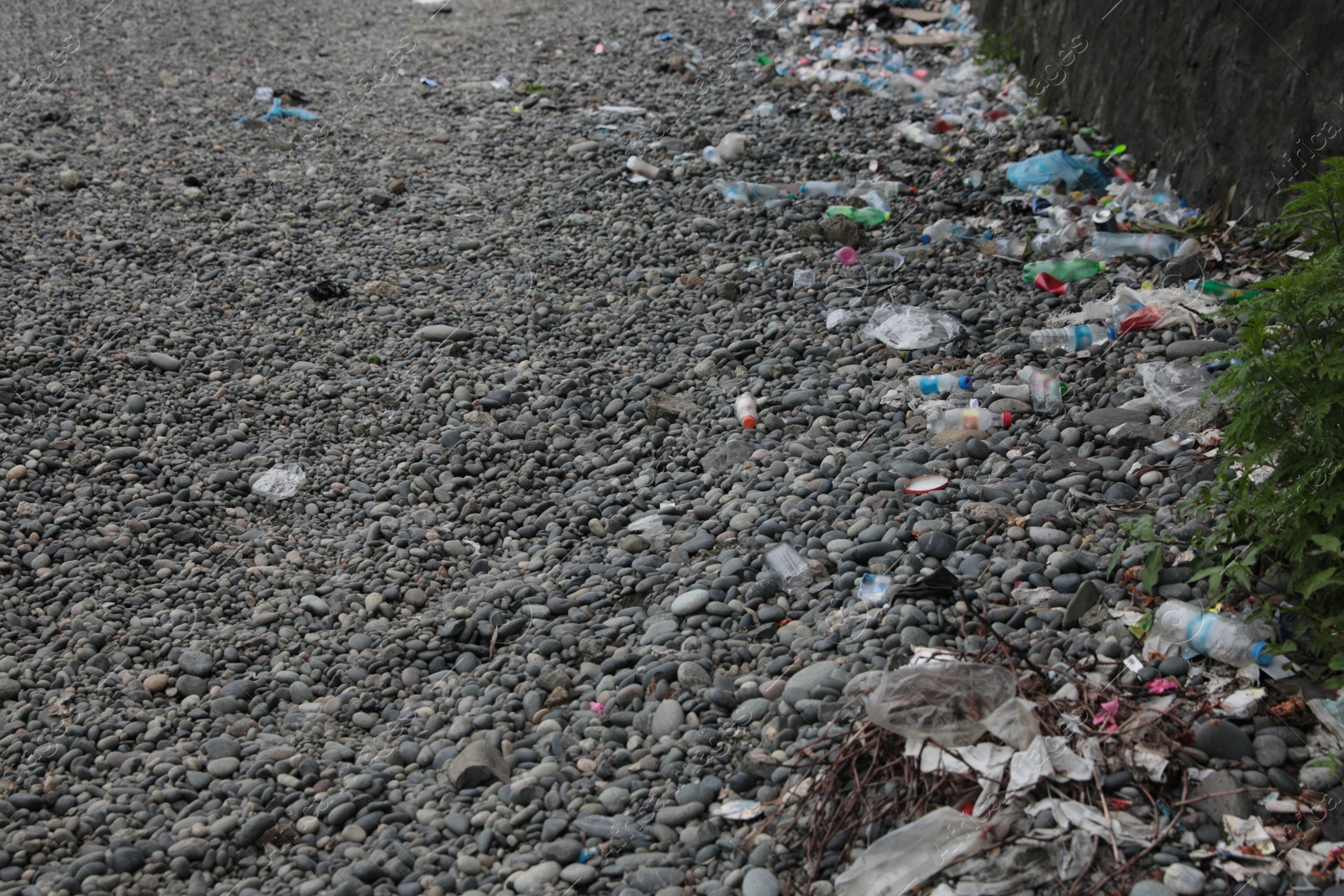 Photo of Garbage scattered on pebbles outdoors. Recycling problem