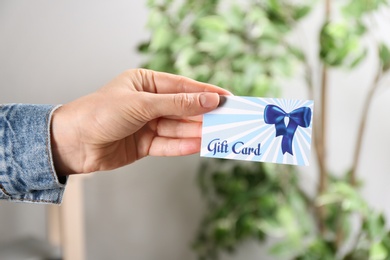 Photo of Woman with gift card on blurred background, closeup