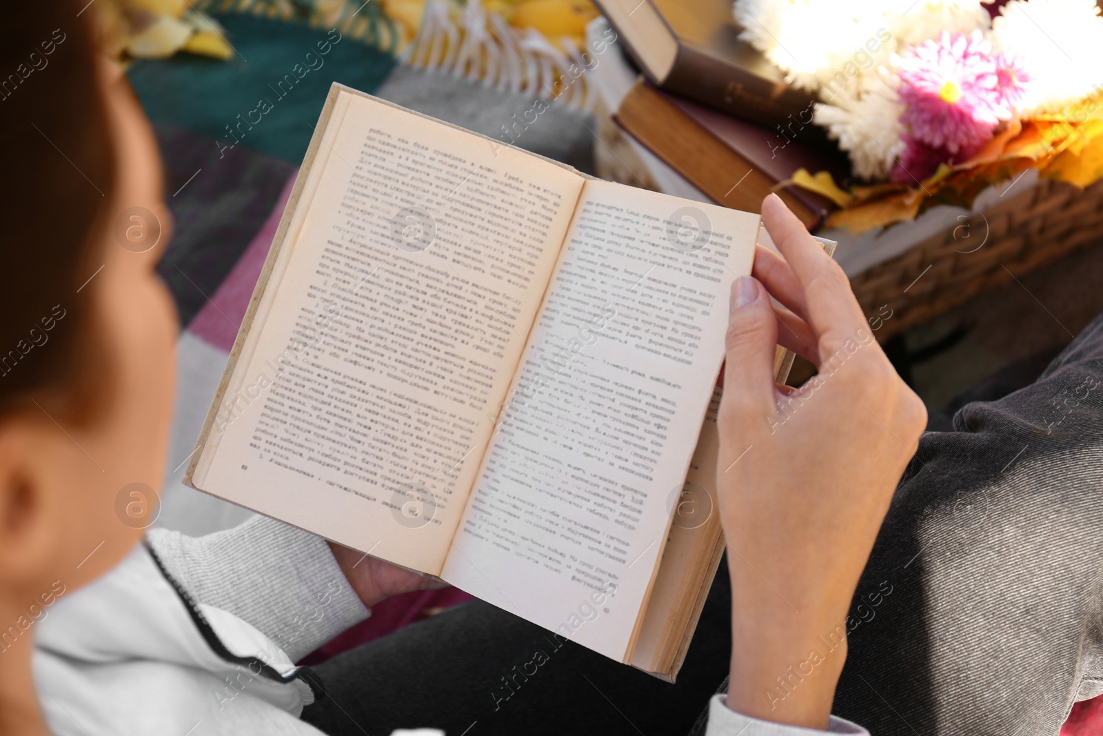 Photo of Woman reading book outdoors on autumn day, closeup