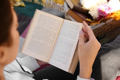 Photo of Woman reading book outdoors on autumn day, closeup