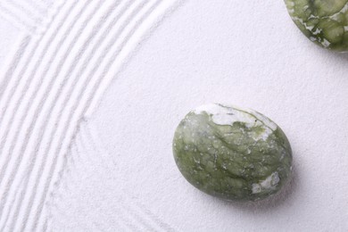 Photo of Stones on sand with pattern, flat lay. Zen concept