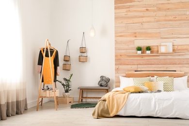 Photo of Stylish room interior with comfortable bed near wooden wall