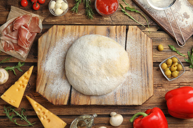 Photo of Flat lay composition with dough and fresh ingredients for pizza on wooden table