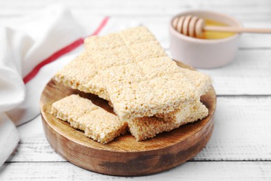 Photo of Wooden board with tasty sesame kozinaki bars on white table, closeup