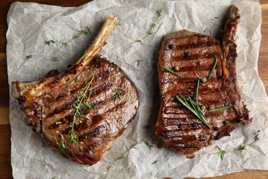 Photo of Tasty grilled meat steaks on board, flat lay