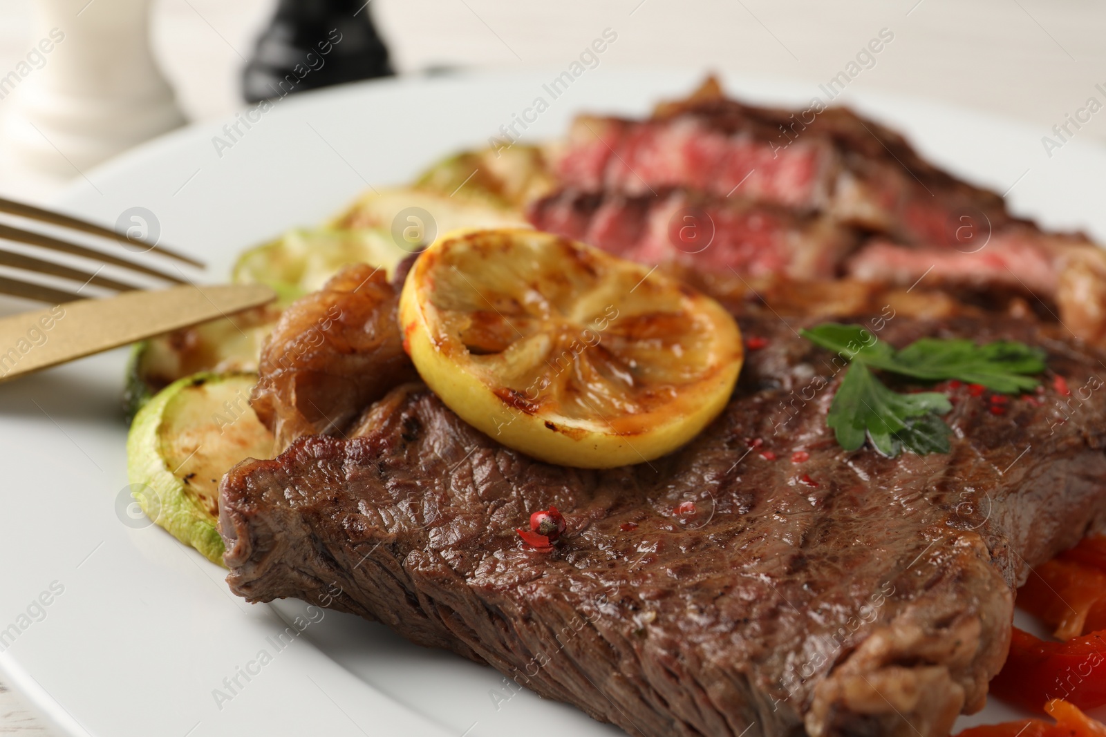 Photo of Delicious grilled beef steak and zucchini on plate, closeup