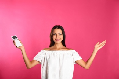 Photo of Young woman with air conditioner remote on pink background