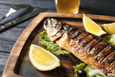 Photo of Wooden board with delicious grilled fish, closeup