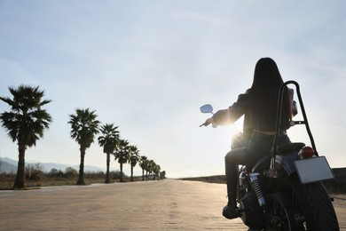 Photo of Woman riding motorcycle at sunset, back view. Space for text