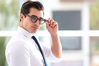 Photo of Handsome young man in stylish clothes with glasses indoors. Space for text