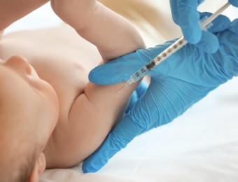 Doctor vaccinating baby in clinic, closeup