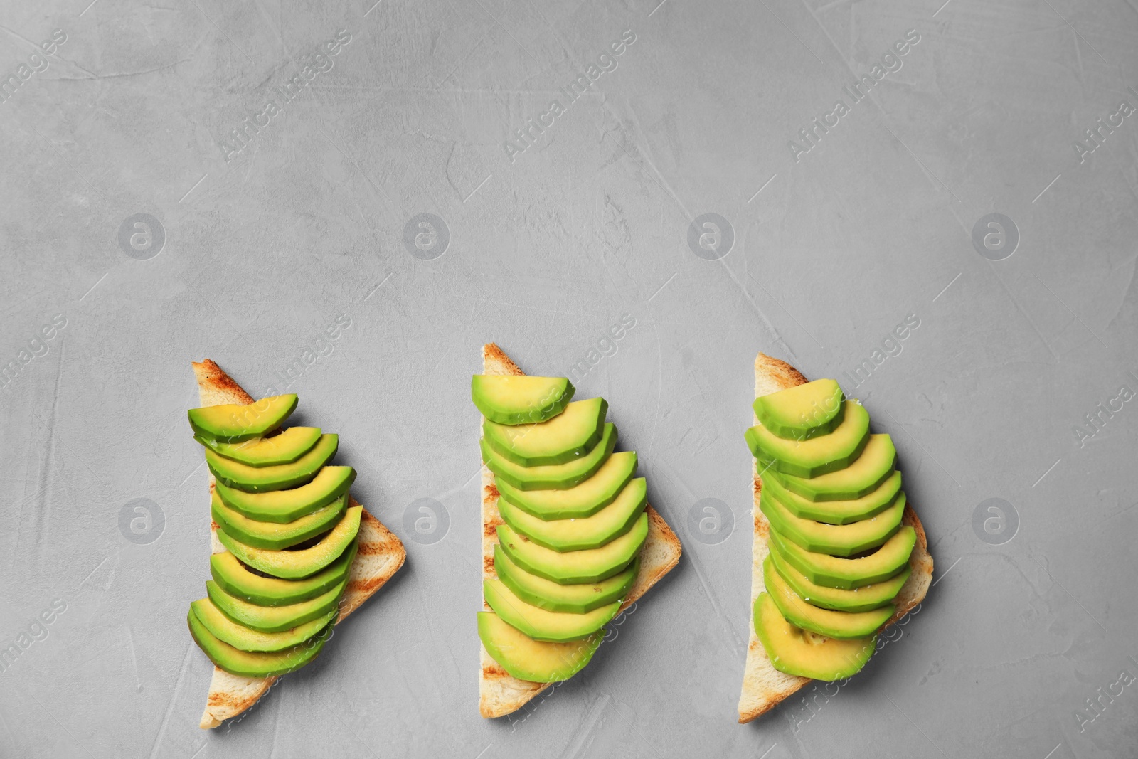 Photo of Tasty toasts with avocado on light grey table, flat lay. Space for text