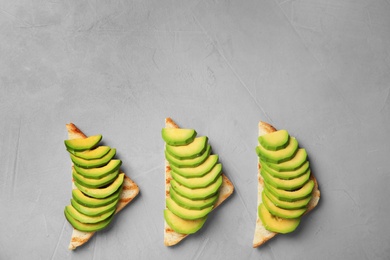 Photo of Tasty toasts with avocado on light grey table, flat lay. Space for text