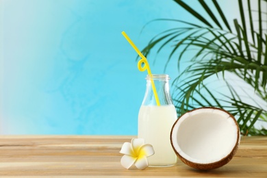 Photo of Composition with bottle of coconut water on wooden table against blue background. Space for text