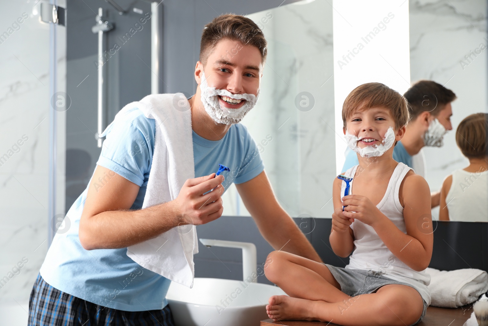 Photo of Dad and son with shaving foam on their faces in bathroom