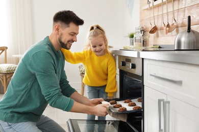 Photo of Father with his daughter baking cookies in oven at home