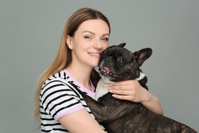 Photo of Portrait of happy woman hugging cute French Bulldog on grey background