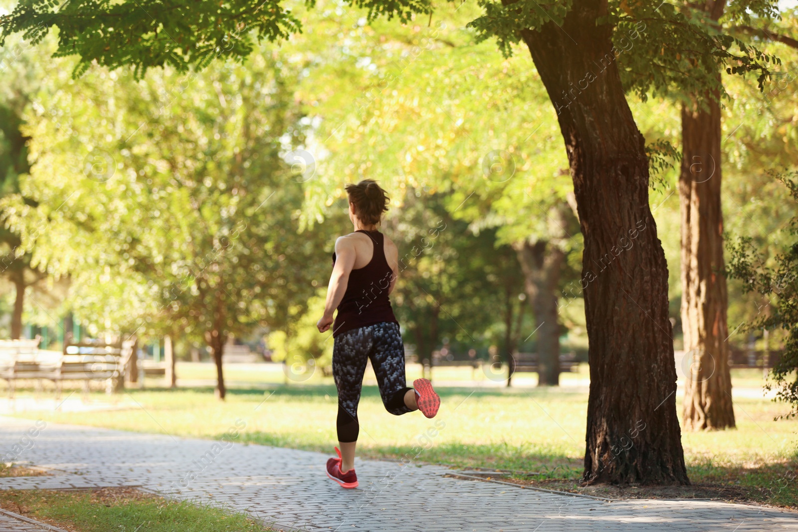 Photo of Young woman running in park on sunny day