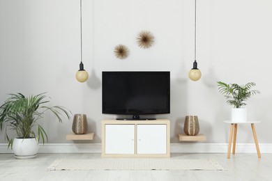 Photo of Modern TV set near white wall in living room