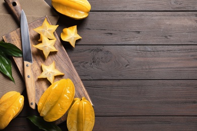 Photo of Delicious carambola fruits on wooden table, flat lay. Space for text