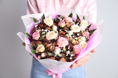 Photo of Woman with beautiful food bouquet on light grey background, closeup