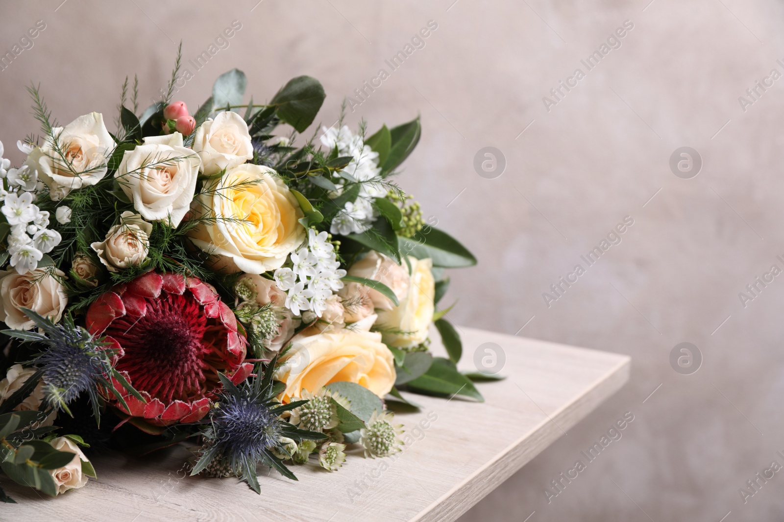 Photo of Beautiful bouquet with roses on white wooden table