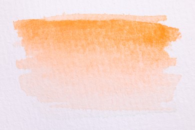 Photo of Abstract orange watercolor painting on white paper, top view