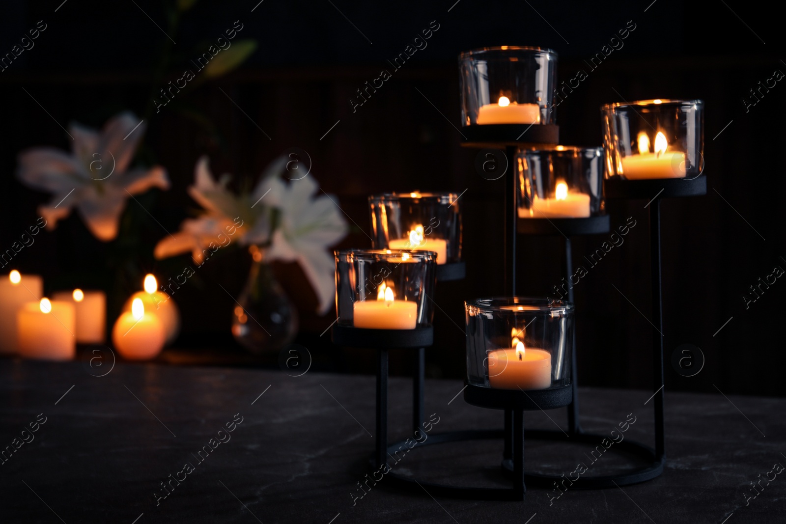 Photo of Holder with burning candles on table in darkness, space for text. Funeral symbol