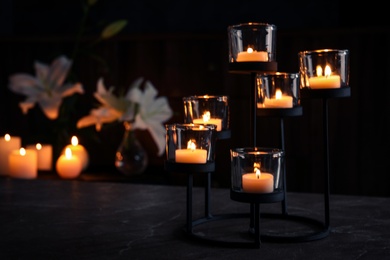 Photo of Holder with burning candles on table in darkness, space for text. Funeral symbol