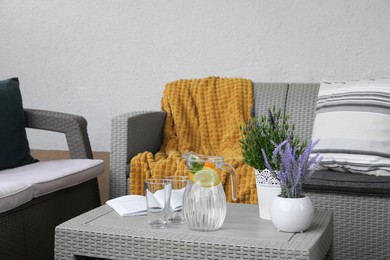 Table with book, jug of water, potted plants and sofas on outdoor terrace