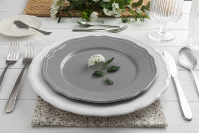 Stylish setting with cutlery, glasses and plates on white wooden table