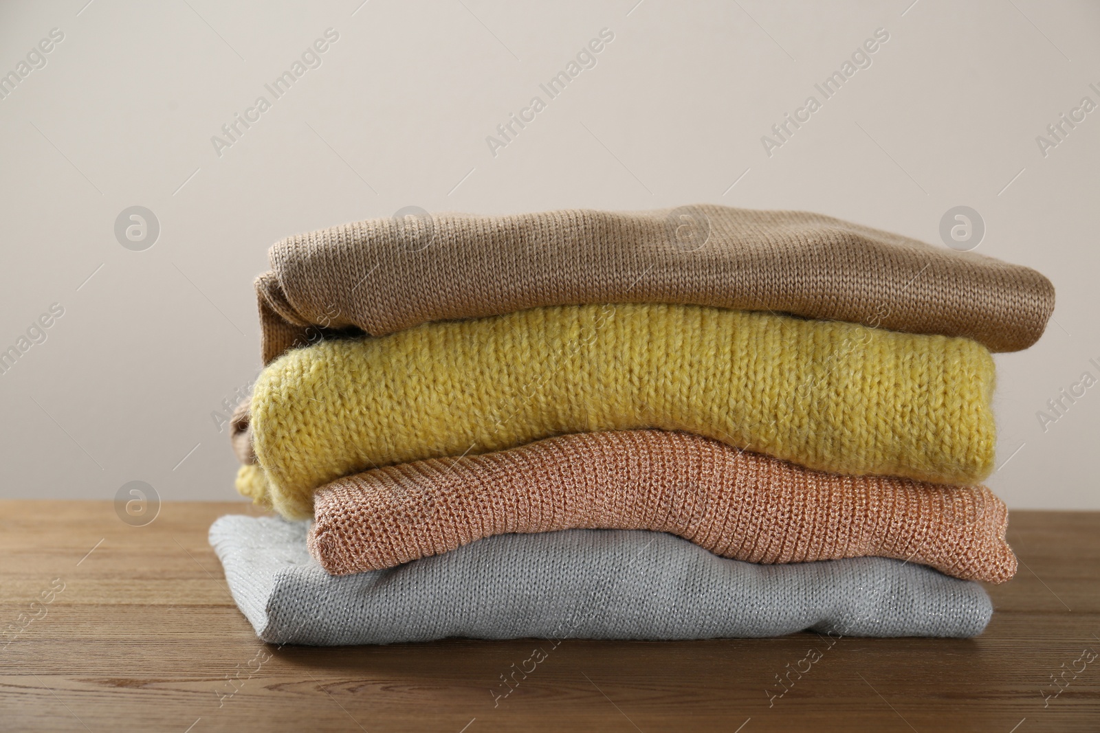 Photo of Stack of knitted sweaters on wooden table