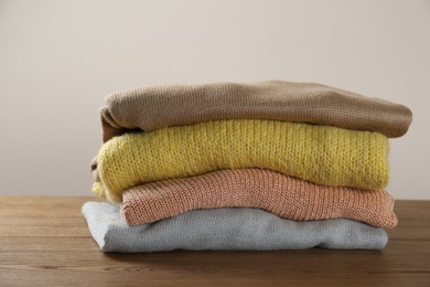 Stack of knitted sweaters on wooden table