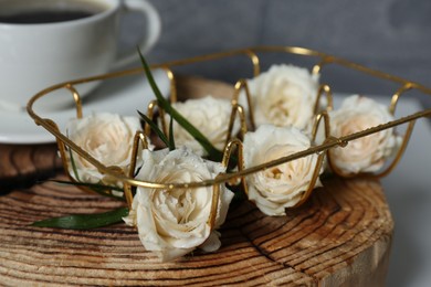 Photo of Decorative gold holder with flowers and cup of coffee on wooden stand, closeup. Interior design