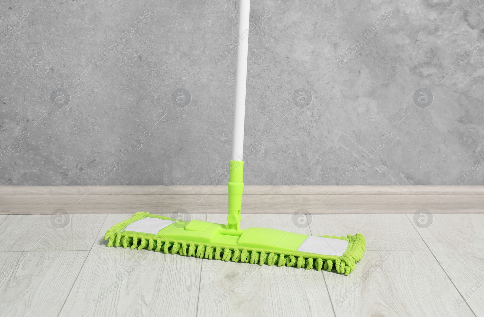 Photo of Mop with plastic handle near wall indoors