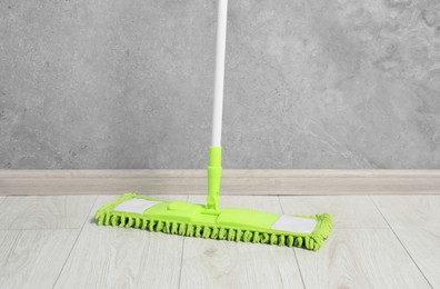 Mop with plastic handle near wall indoors