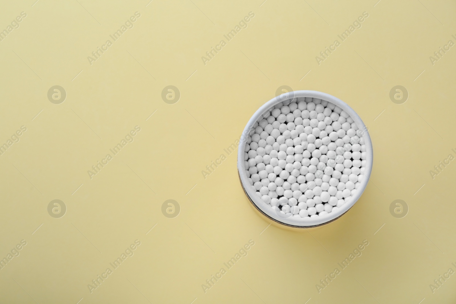 Photo of Container with new cotton buds on beige background, top view. Space for text