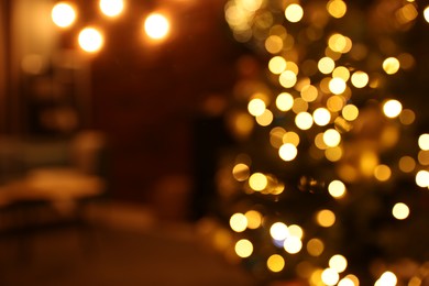 Blurred view of beautiful Christmas tree with festive lights indoors. Bokeh effect